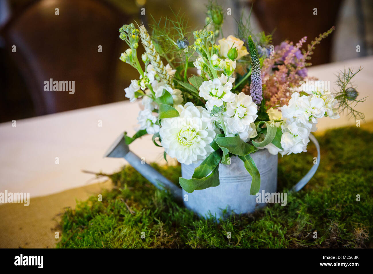 Table de mariage arrangement de fleurs en arrosoir, sur la mousse Banque D'Images