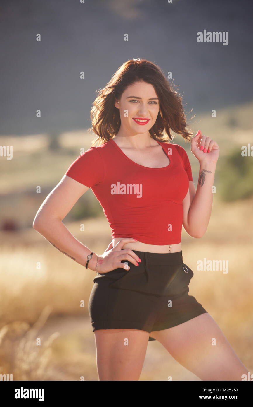 Belle brunette girl wearing short noir et un t-shirt rouge dans la campagne  Photo Stock - Alamy