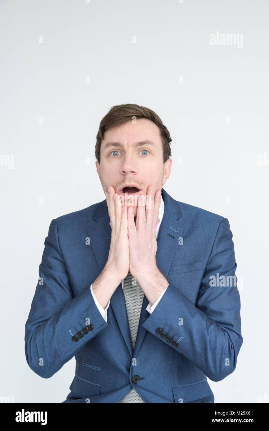 Portrait d'un homme bien habillé dans un costume à choqué et désemparé dans à l'appareil photo. Isolé sur fond blanc Banque D'Images