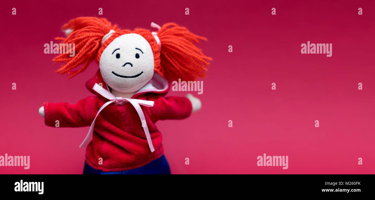 Le petit chaperon rouge et sourire mignon femelle ou d'une fille ou d'un tissu rag doll avec des nattes isolé sur fond rouge Banque D'Images