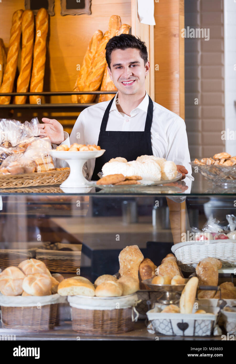 Jeune homme heureux de vendre des tartes et des pâtisseries dans le café-house Banque D'Images