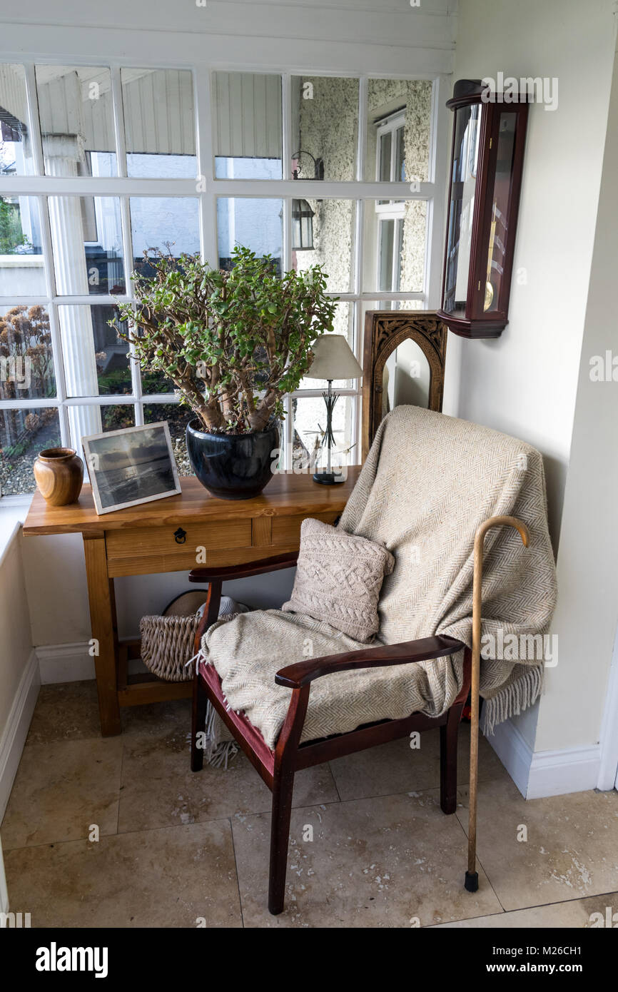 Vide chaise confortable sur un porche avec une couverture voussures et un  bâton de marche en appui sur le fauteuil Photo Stock - Alamy