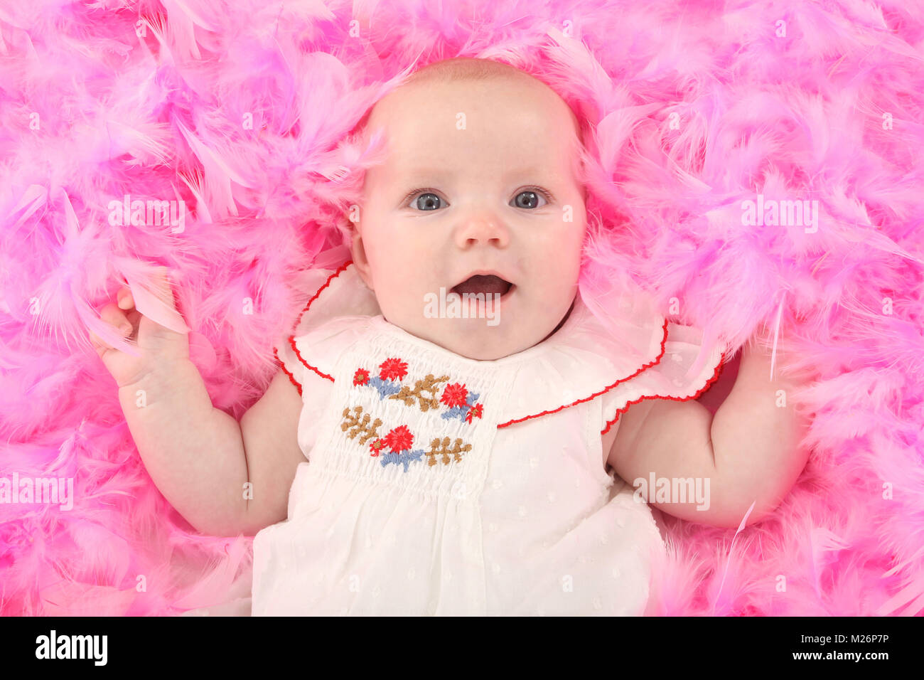 Beau bébé de trois mois fille heureux de jouer en plumes roses Banque D'Images
