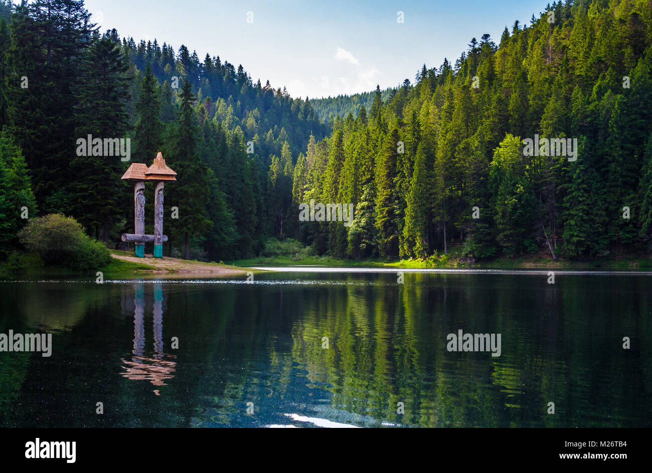 Beau paysage de lac Synevyr. forêt de sapins en soir lumière reflète dans l'eau ridée de vue faible. Banque D'Images