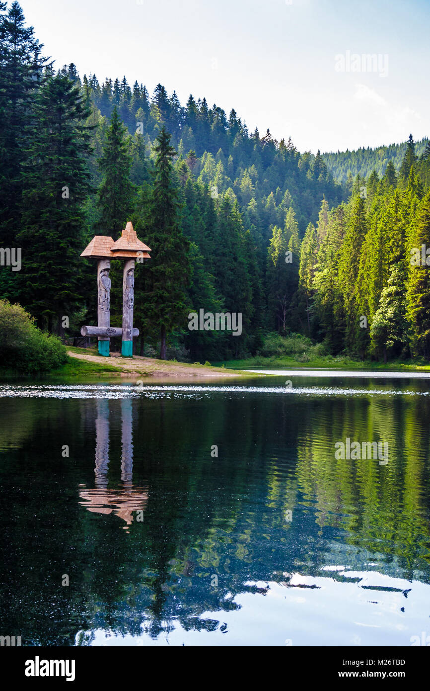 Beau paysage de lac Synevyr. forêt de sapins en soir lumière reflète dans l'eau ridée de vue faible. Banque D'Images