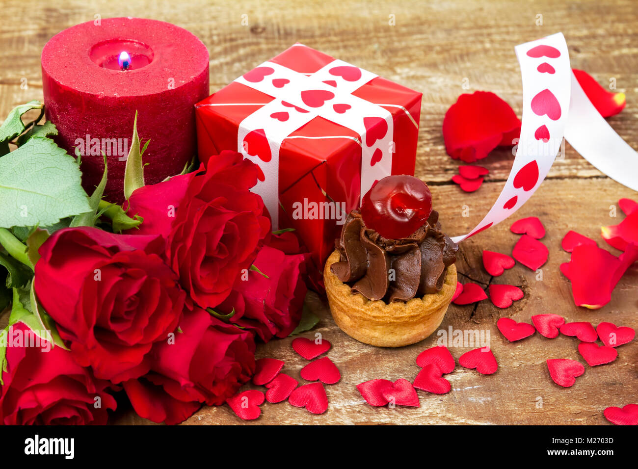 Avec cherry Cupcake en face de bouquet de roses rouges et des bougies sur fond de bois. Valentines Day concept. Se concentrer sur des gâteaux ! Banque D'Images
