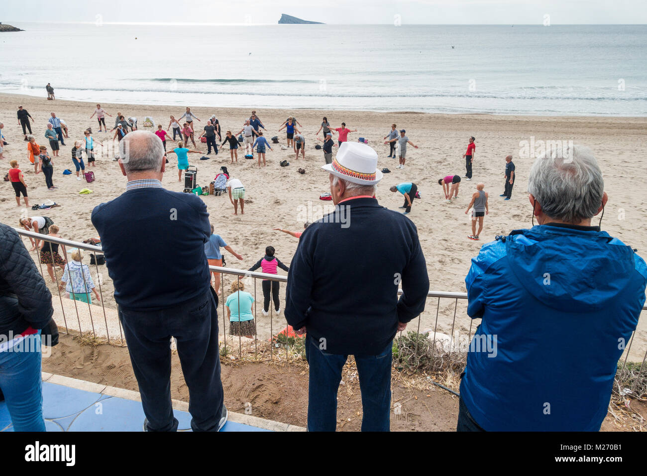 Les personnes âgées garder l'ajustement sur la plage de Benidorm, Espagne. Hommes Femmes Dao, la classe fitness personnes âgées spectateurs regardant et participer. Banque D'Images