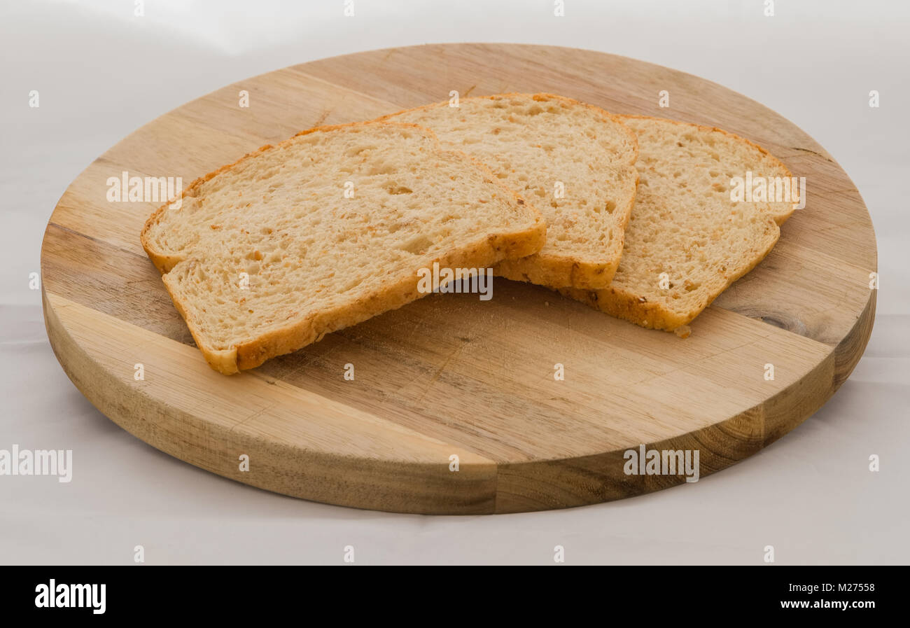 Trois tranches de pain brun sain sur une planche à découper en bois avec suffisamment de place pour le texte. Banque D'Images