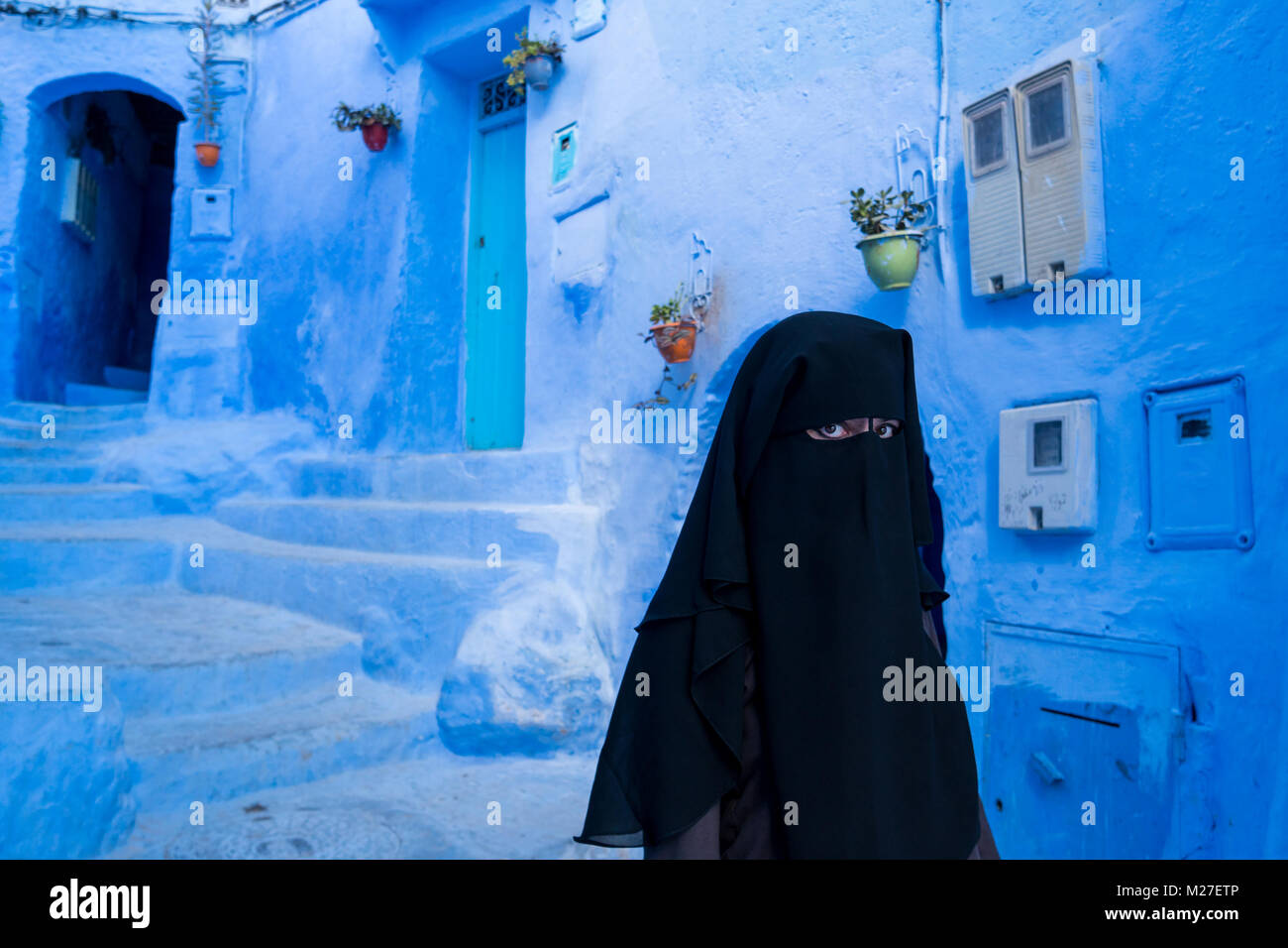 Femme arabe à visage couvert de niqab noir à Chefchaouen, la ville bleue, au Maroc Banque D'Images