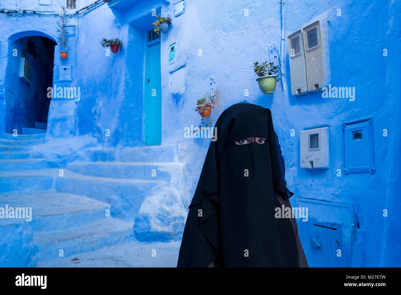 Femme arabe à visage couvert de niqab noir à Chefchaouen, la ville bleue, au Maroc Banque D'Images