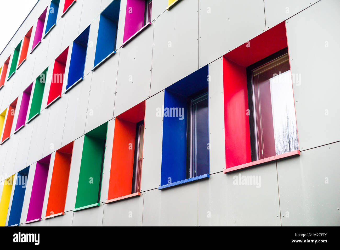 Façade d'un immeuble récemment rénové avec isolation par l'extérieur, recouvert de panneaux métalliques grises et des cadres de fenêtre qui sont peints avec des col Banque D'Images