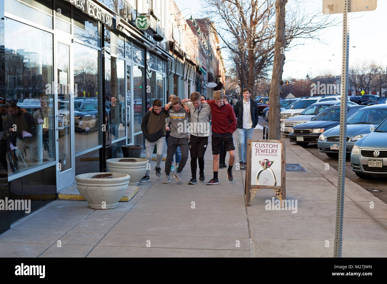 Un groupe d'amis se bloque les bras et éviter le trottoir à Fort Collins, Colorado, USA. Banque D'Images