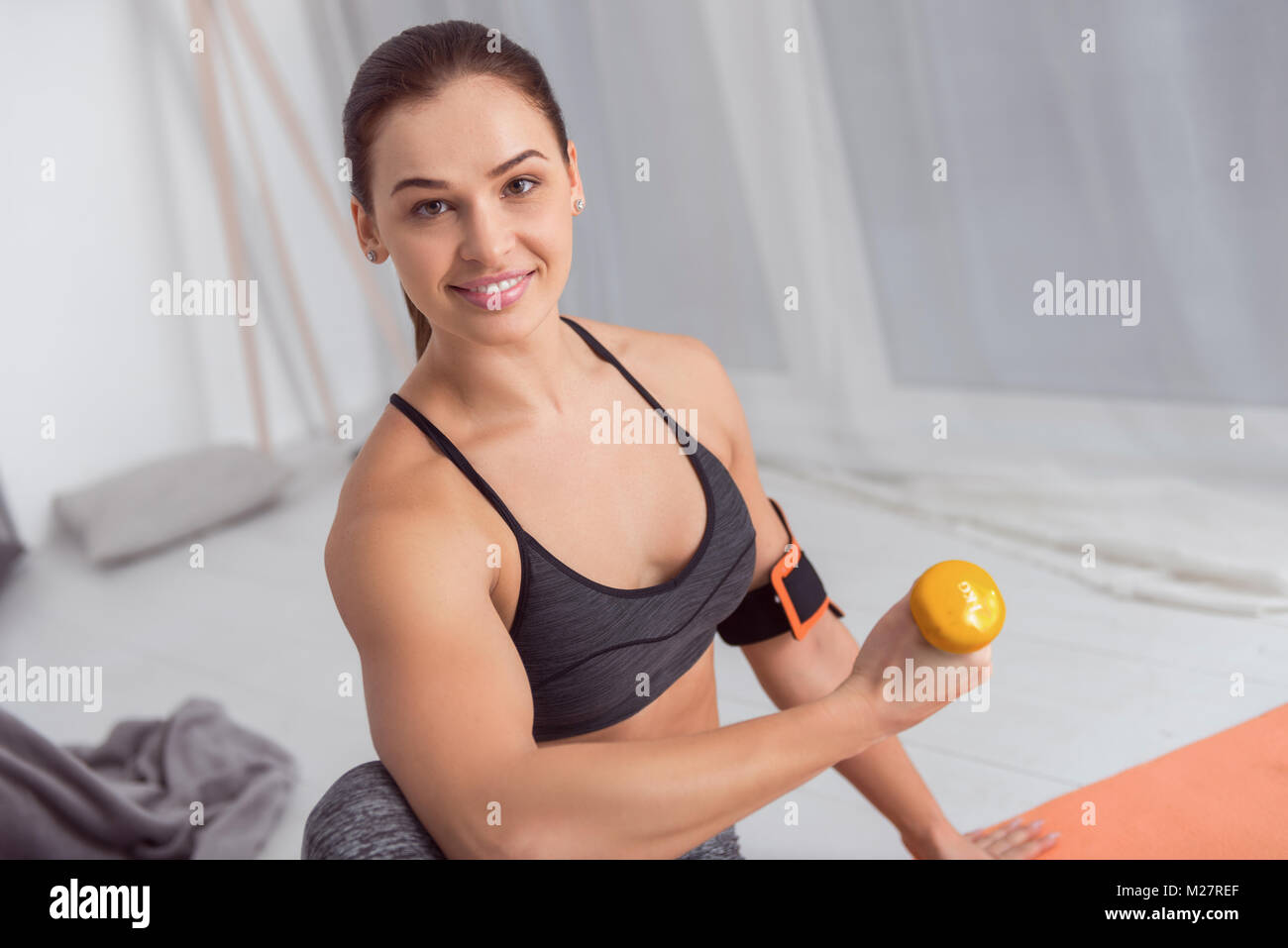 Femme souriante faisant des exercices avec haltères à la maison Banque D'Images