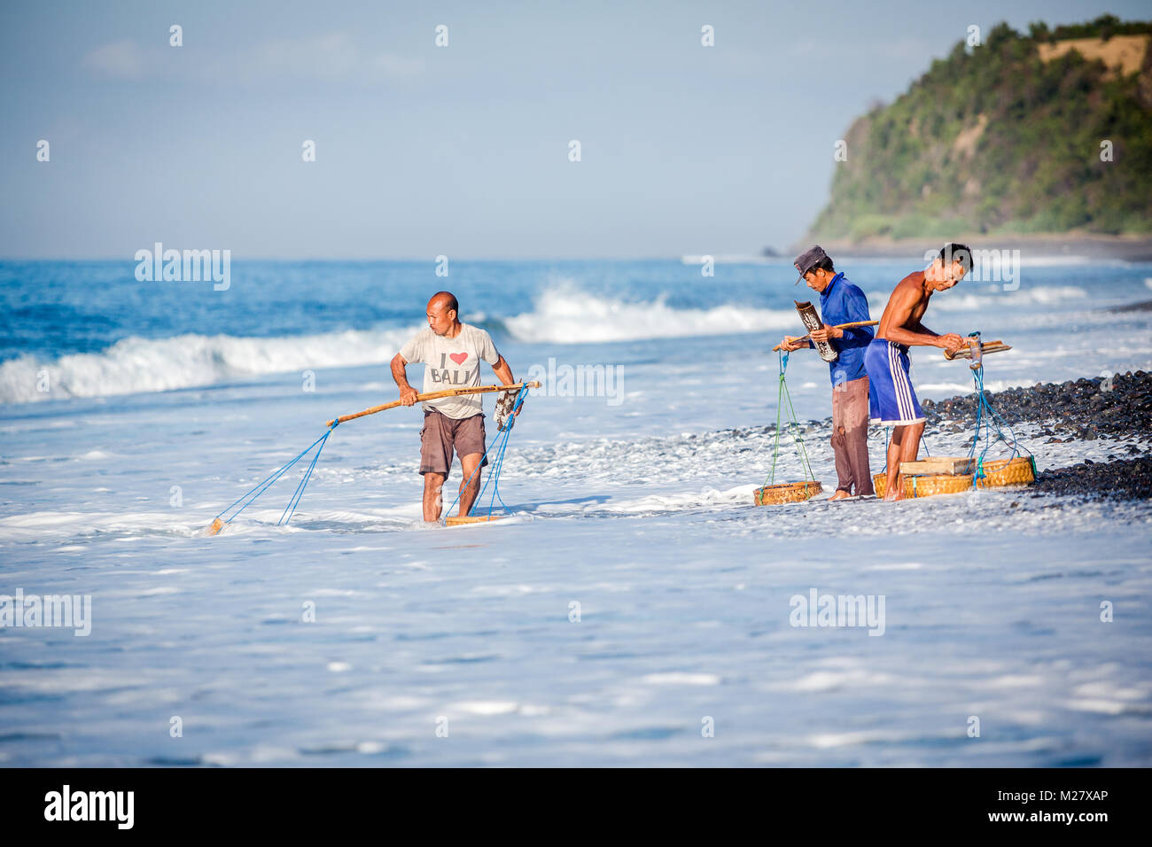 Bali, 31 août 2013 : Un homme recueille des cailloux lisser à la plage à Bali, Indonésie. Par l'arrondi des pierres et la mer de sable a valeur industrielle fo Banque D'Images