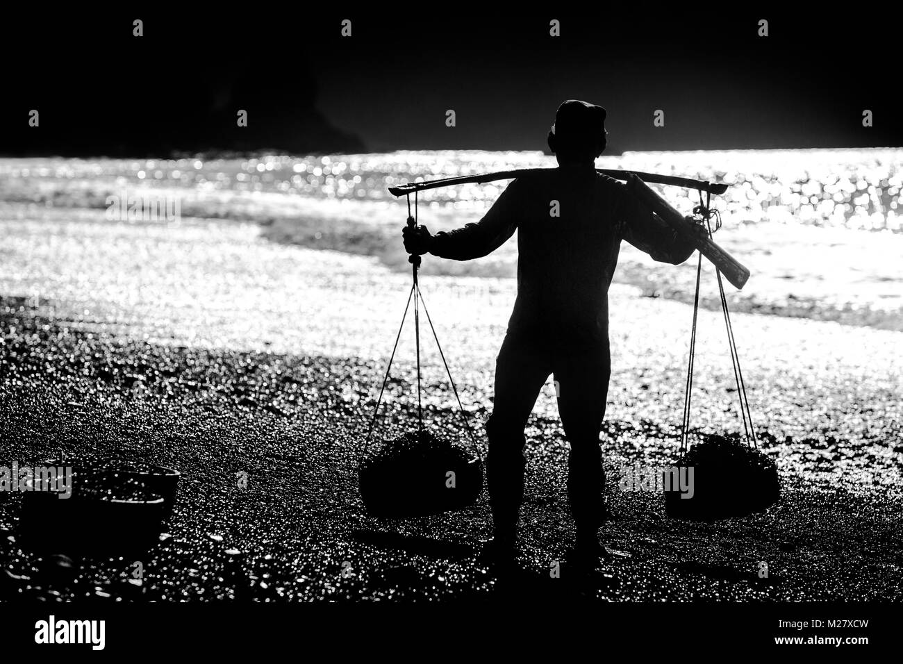 Bali, 31 août 2013 : Un homme recueille des cailloux lisser à la plage à Bali, Indonésie. Par l'arrondi des pierres et la mer de sable a valeur industrielle fo Banque D'Images