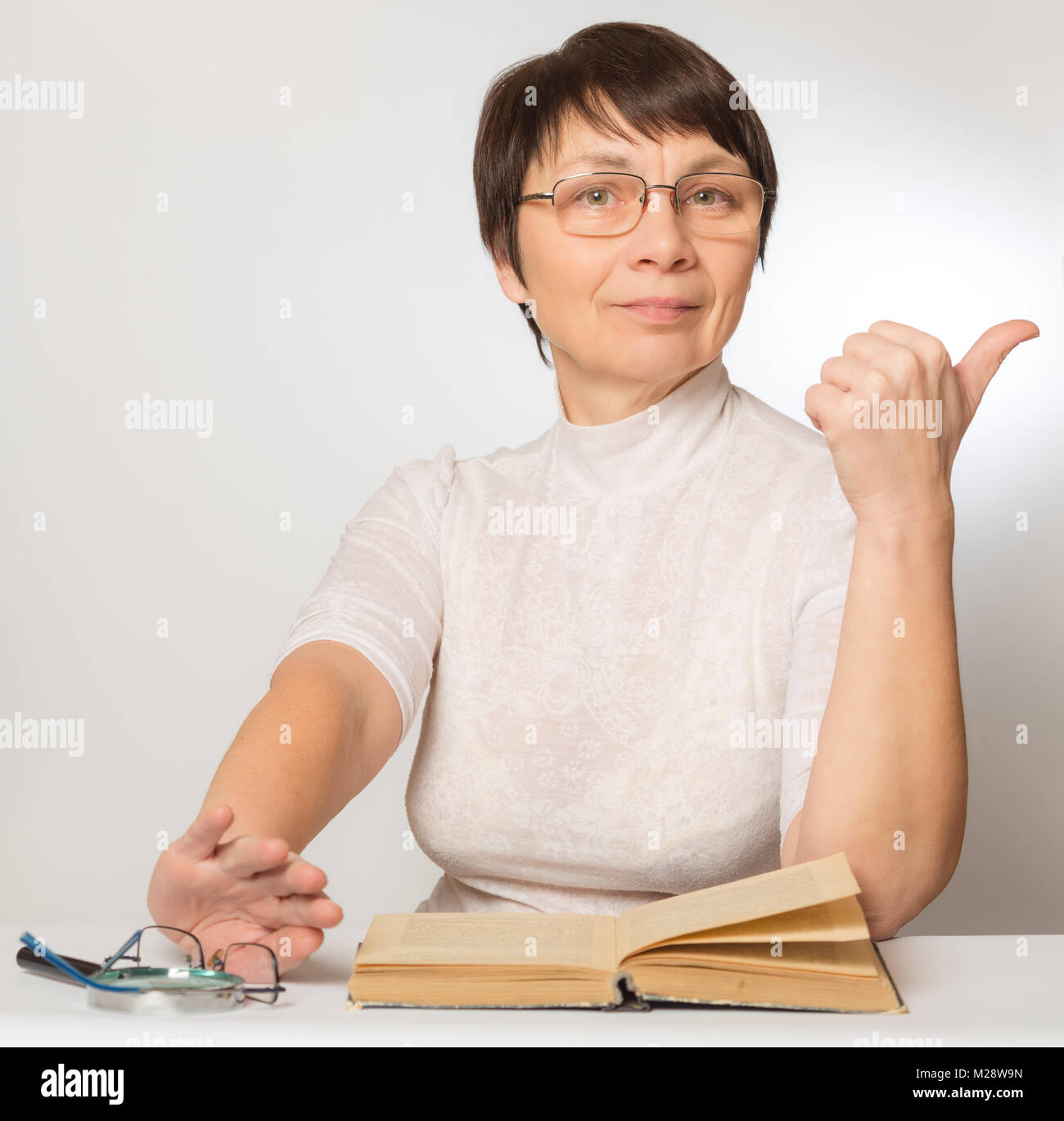 Femme de la nouvelles lunettes montre un signe qu'elle se porte bien et pousse vieux verres et d'une loupe Banque D'Images