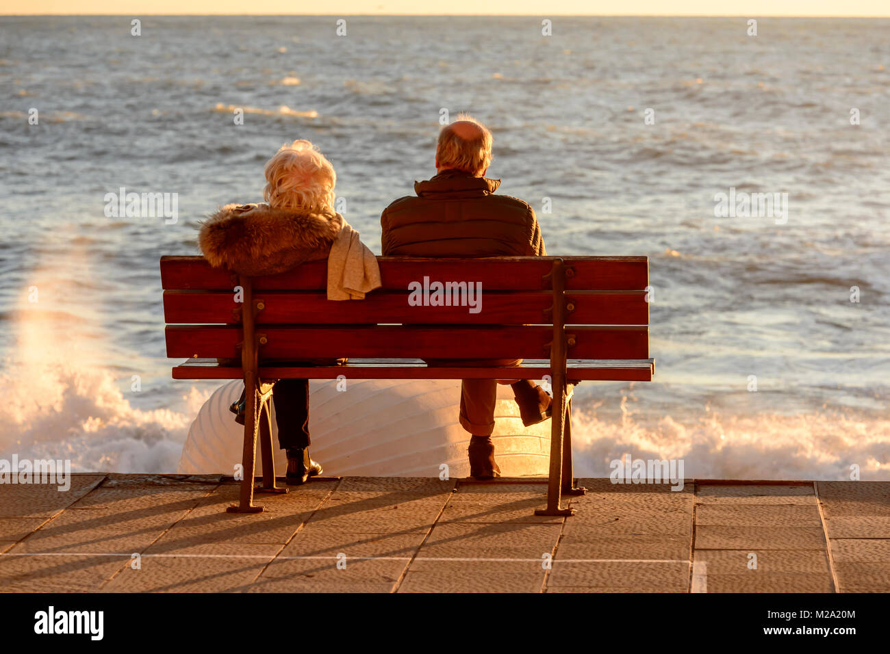 Deux aînés méconnaissable s'asseoir sur banc en face de la mer à village touristique, tourné sur une journée d'hiver ensoleillée, Camogli, Italie Banque D'Images