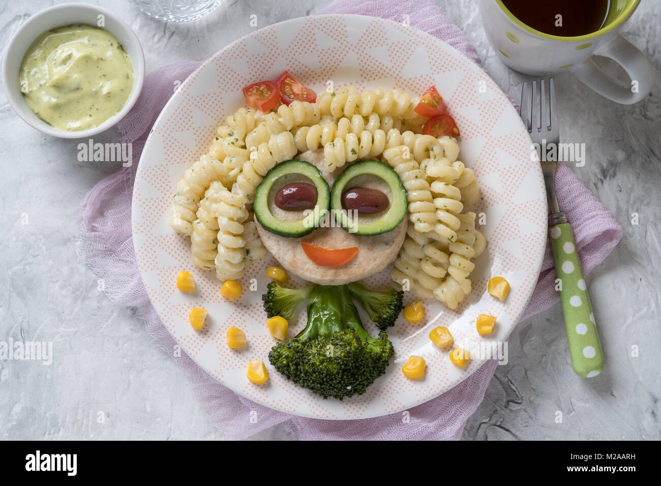 Funny Girl face à la nourriture avec l'escalope de poulet, pâtes et légumes Banque D'Images