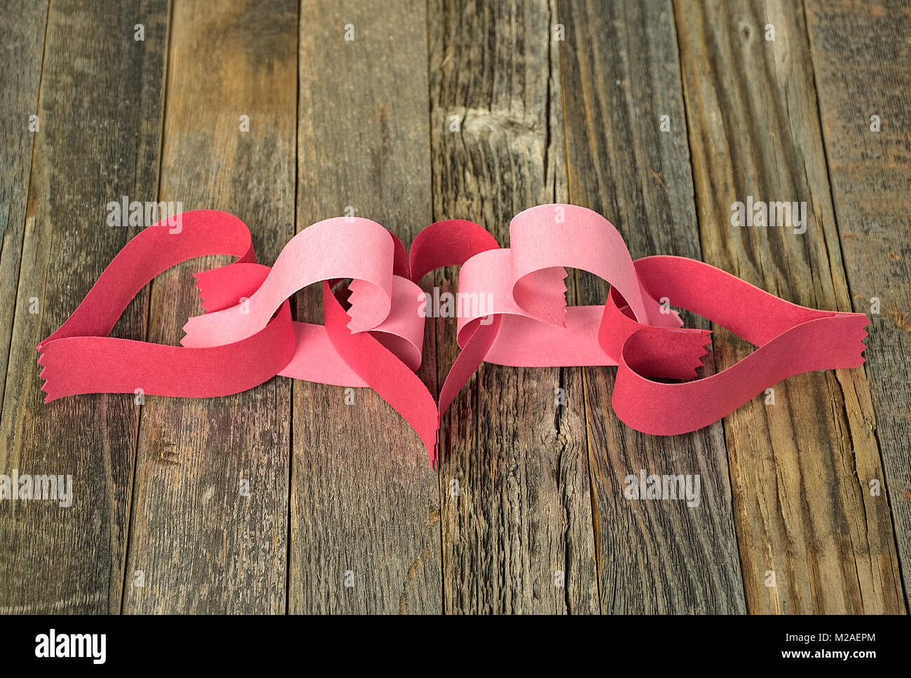 Gros plan du papier rose et rouge valentine la chaîne sur le bois rustique Banque D'Images