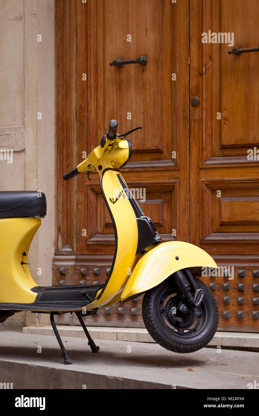 Juste assez de place de parking pour ce petit moteur jaune scooter à la porte avant, Montalcino, Toscane, Italie Banque D'Images