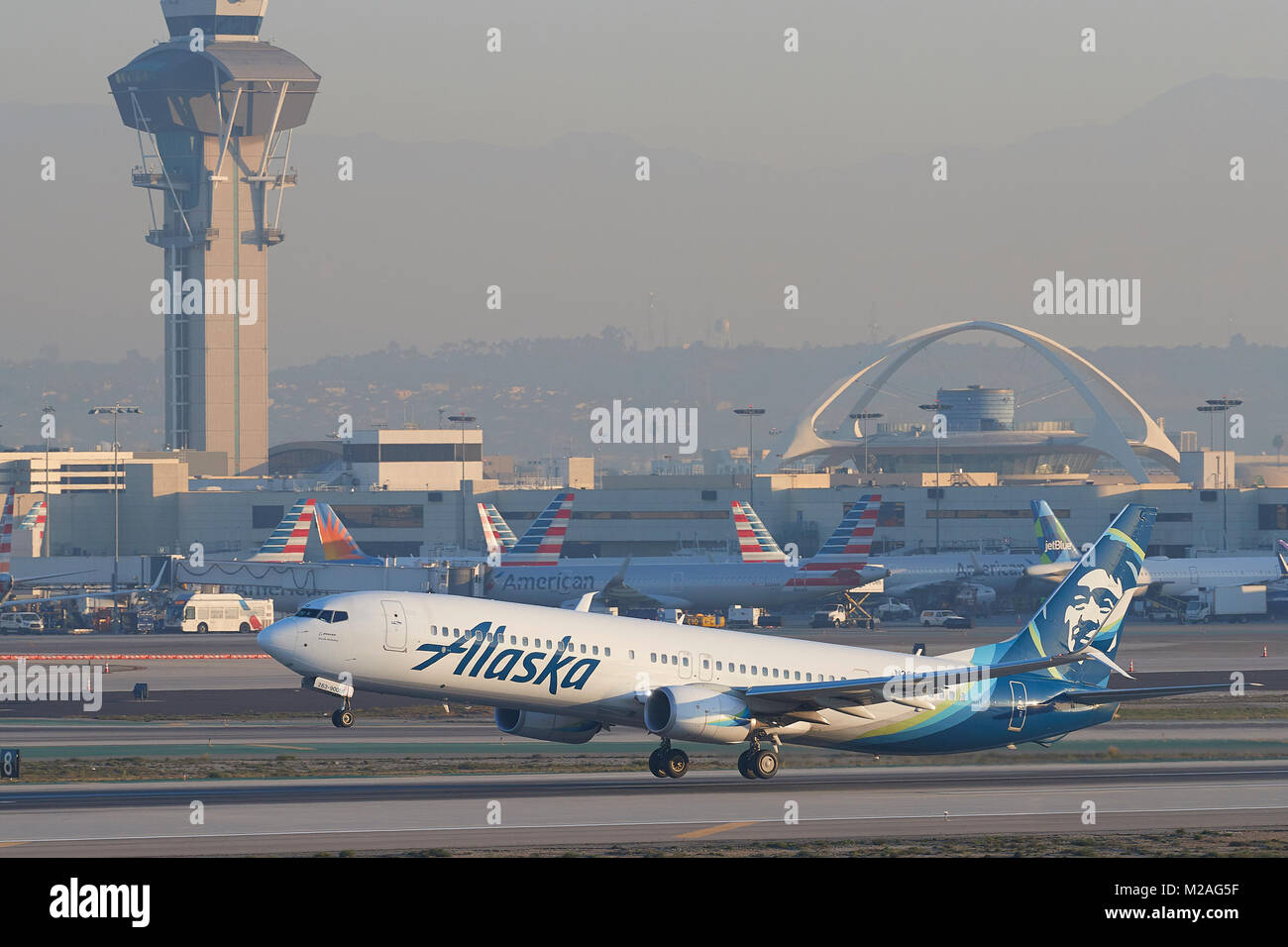 Alaska Airlines Boeing 737-900ER, avion de ligne, décoller de la piste 25 gauche à l'Aéroport International de Los Angeles, la tour de contrôle en arrière-plan. Banque D'Images