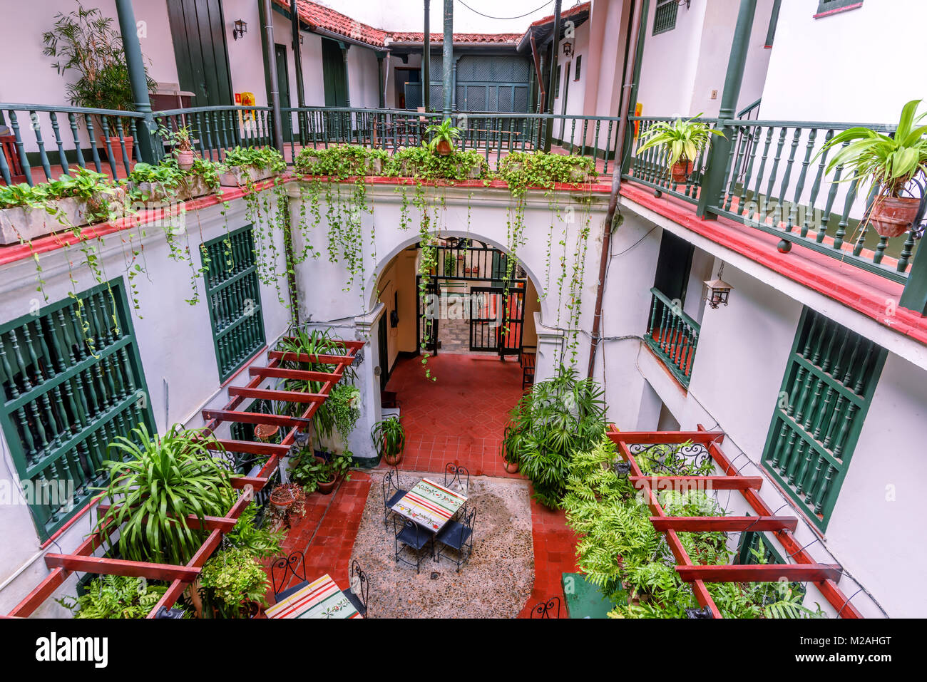 Vue de dessus d'une ancienne cour de style espagnol avec des murs blancs, des colonnes rouges, tables carrées avec mosaïque et vert plantes d'intérieur Banque D'Images