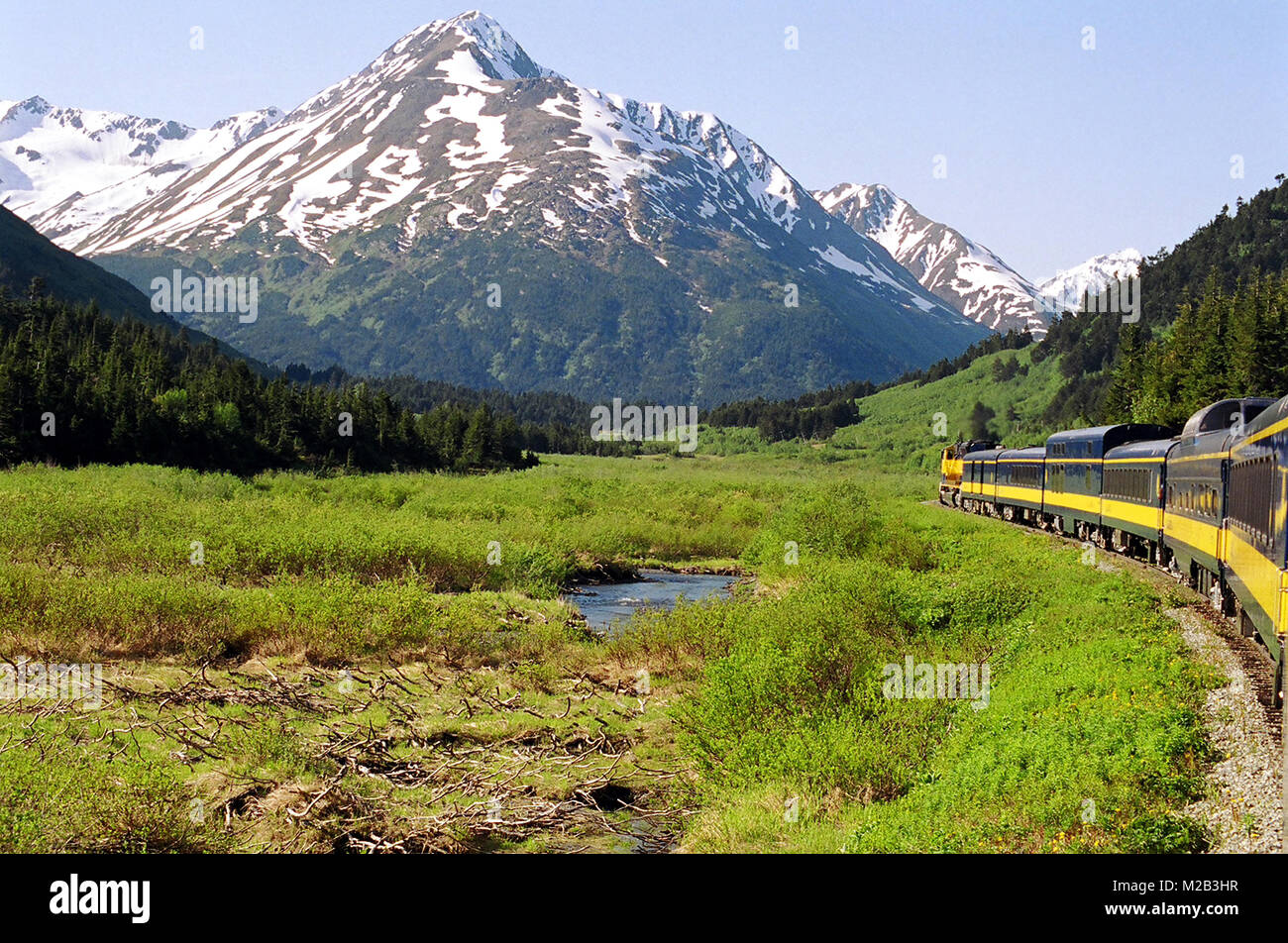 La magnifique nature montagneuse enneigée de l'Alaska, vue depuis la dernière voiture de ce train, en route vers le parc national Denali. Banque D'Images