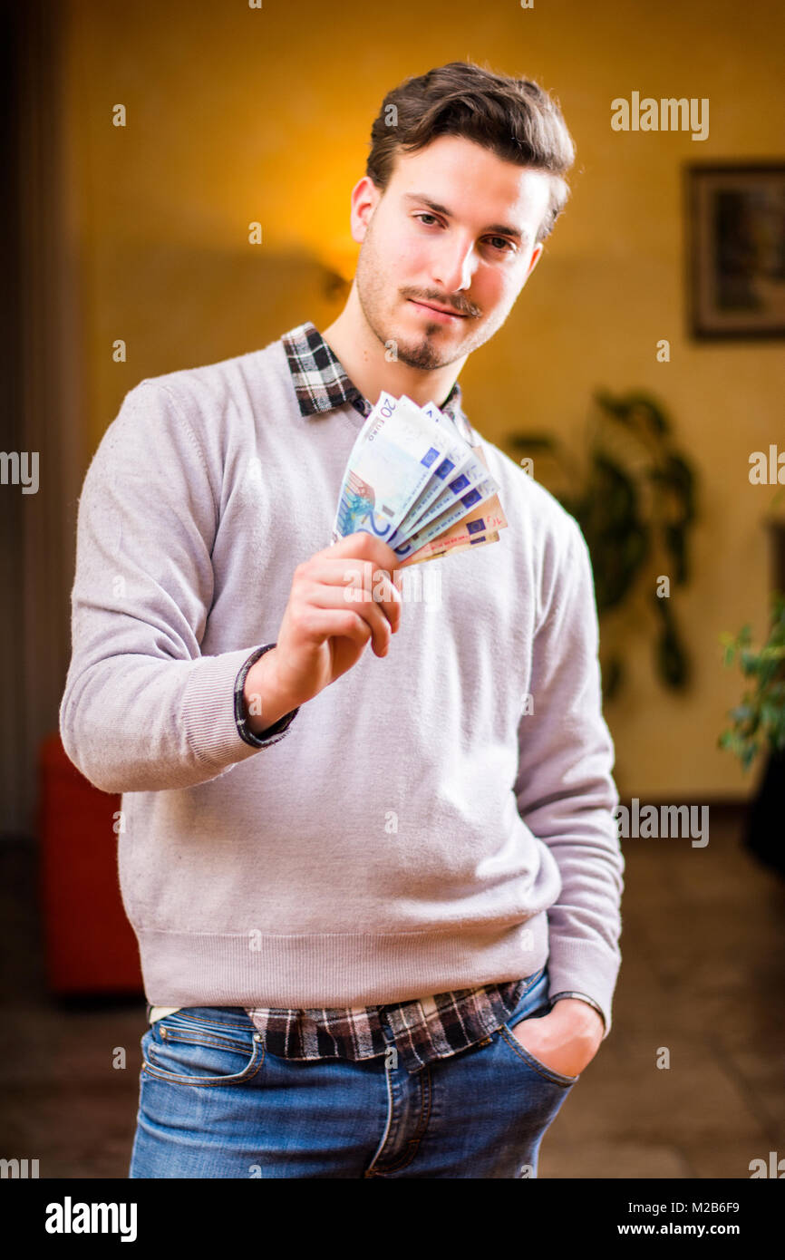 Beau jeune homme de l'argent comptant, à l'intérieur tourné Banque D'Images