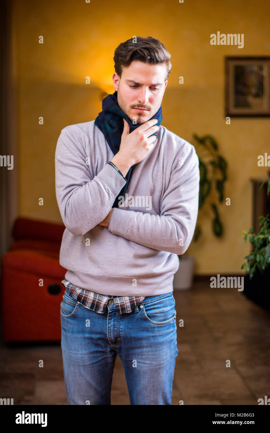 Jeune homme avec écharpe, tenant son cou à cause de maux de gorge Banque D'Images