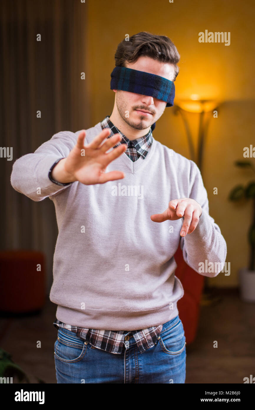 Jeune homme, les yeux bandés, à la maison dans la salle de séjour ne peuvent pas voir Banque D'Images