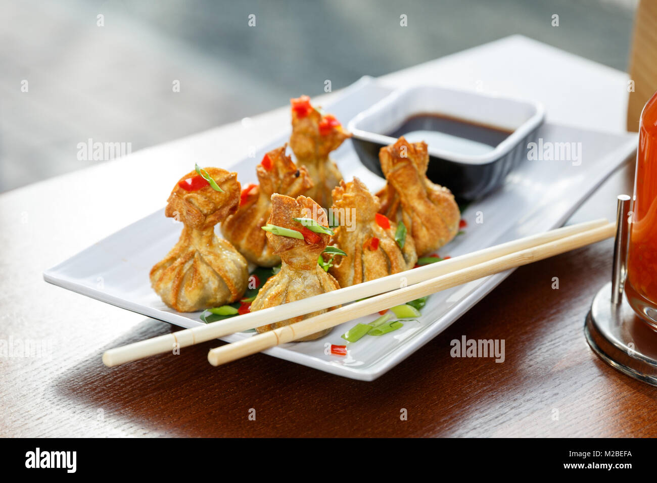 Partie de six wontons frits sur une assiette avec des bâtons, debout sur une table Banque D'Images