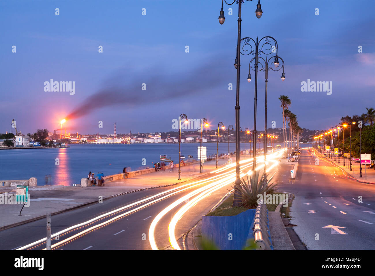 Ave Carlos Manuel Cespedes (Avenue del Puerto) au crépuscule avec la raffinerie de pétrole de Ñico López et le Port de La Havane en arrière-plan. La Vieille Havane, Cuba. Banque D'Images