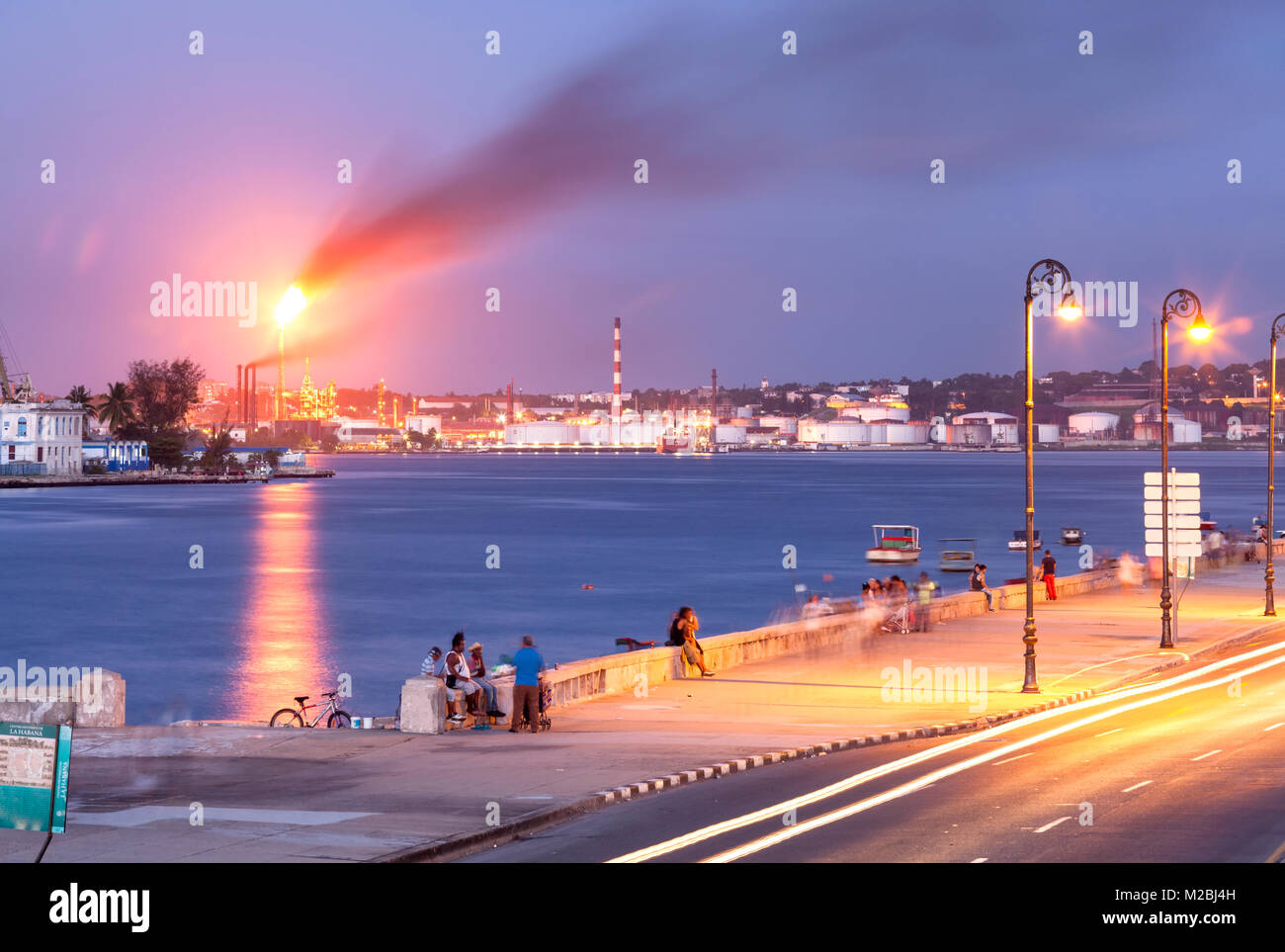 Ave Carlos Manuel Cespedes (Avenue del Puerto) au crépuscule avec la raffinerie de pétrole de Ñico López et le Port de La Havane en arrière-plan. La Vieille Havane, Cuba. Banque D'Images