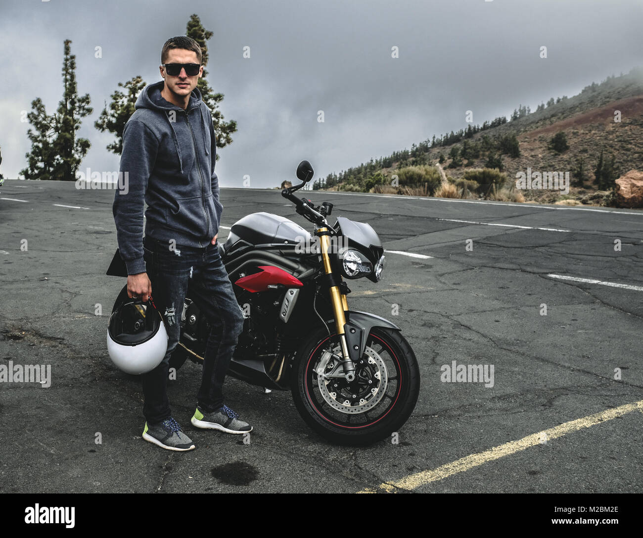 Stand rider sur une montagne à côté de motorcycle Banque D'Images