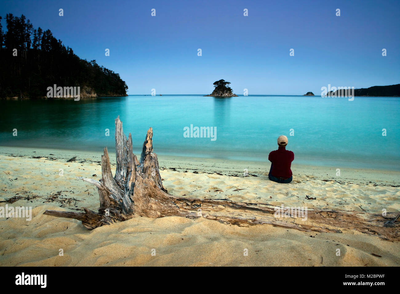 Nouvelle Zélande, île du Sud, parc national Abel Tasman. Woman relaxing at seashore au crépuscule. Banque D'Images