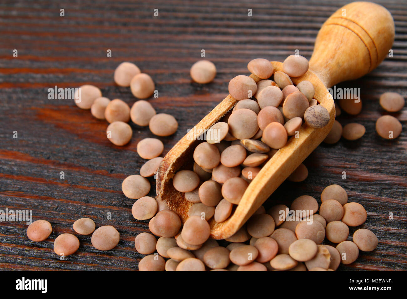 Les lentilles rouges dans un scoop en bois sur une table en bois Banque D'Images