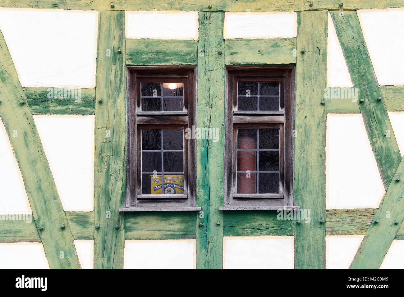 Un gros plan de deux petites fenêtres dans une maison avec des poutres en bois vertes. Le vieux bois et le design simple donnent à la maison un aspect rustique et champêtre. Banque D'Images
