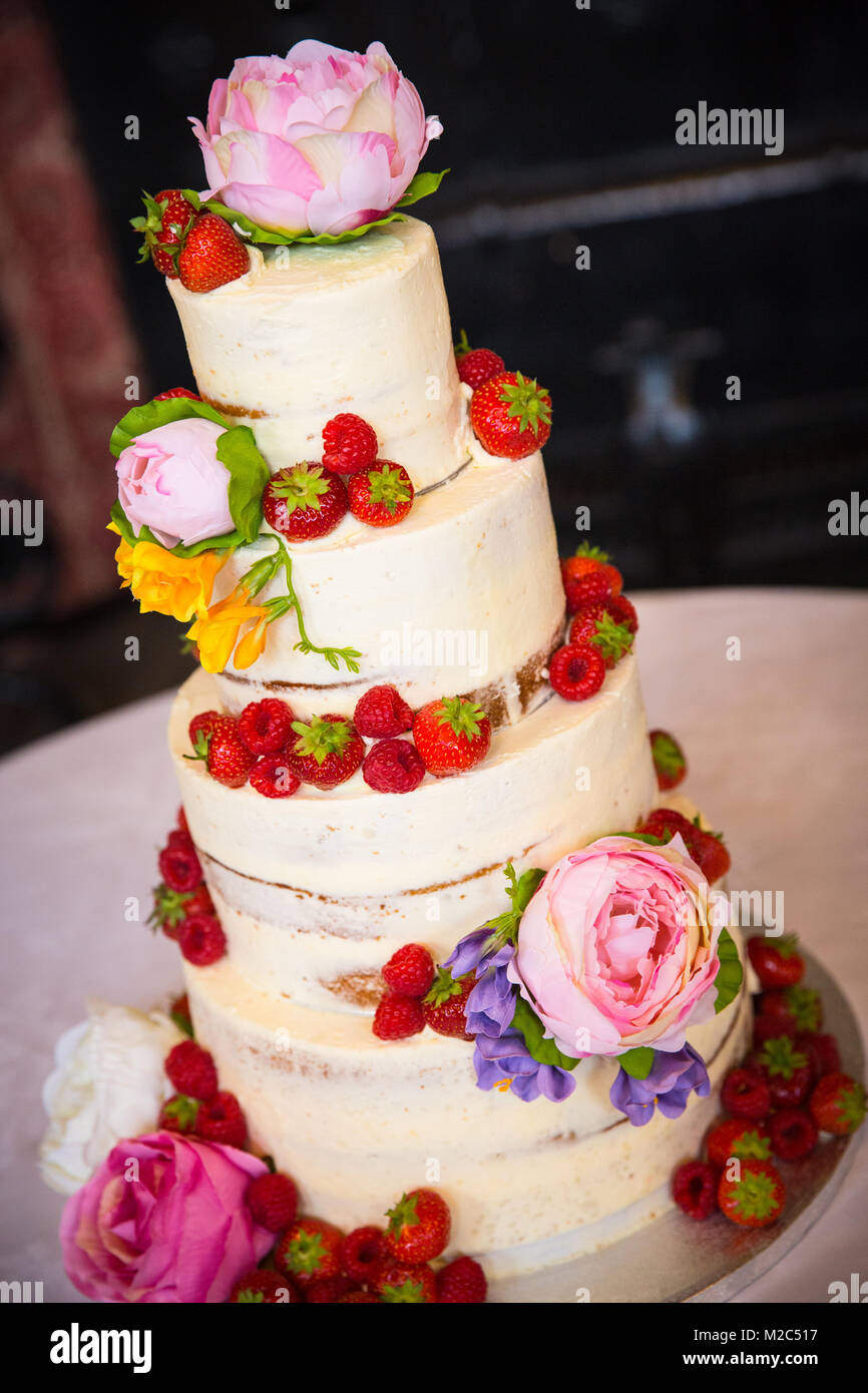 Des fleurs fraîches et des fruits sur gâteau de célébration à plusieurs niveaux Banque D'Images