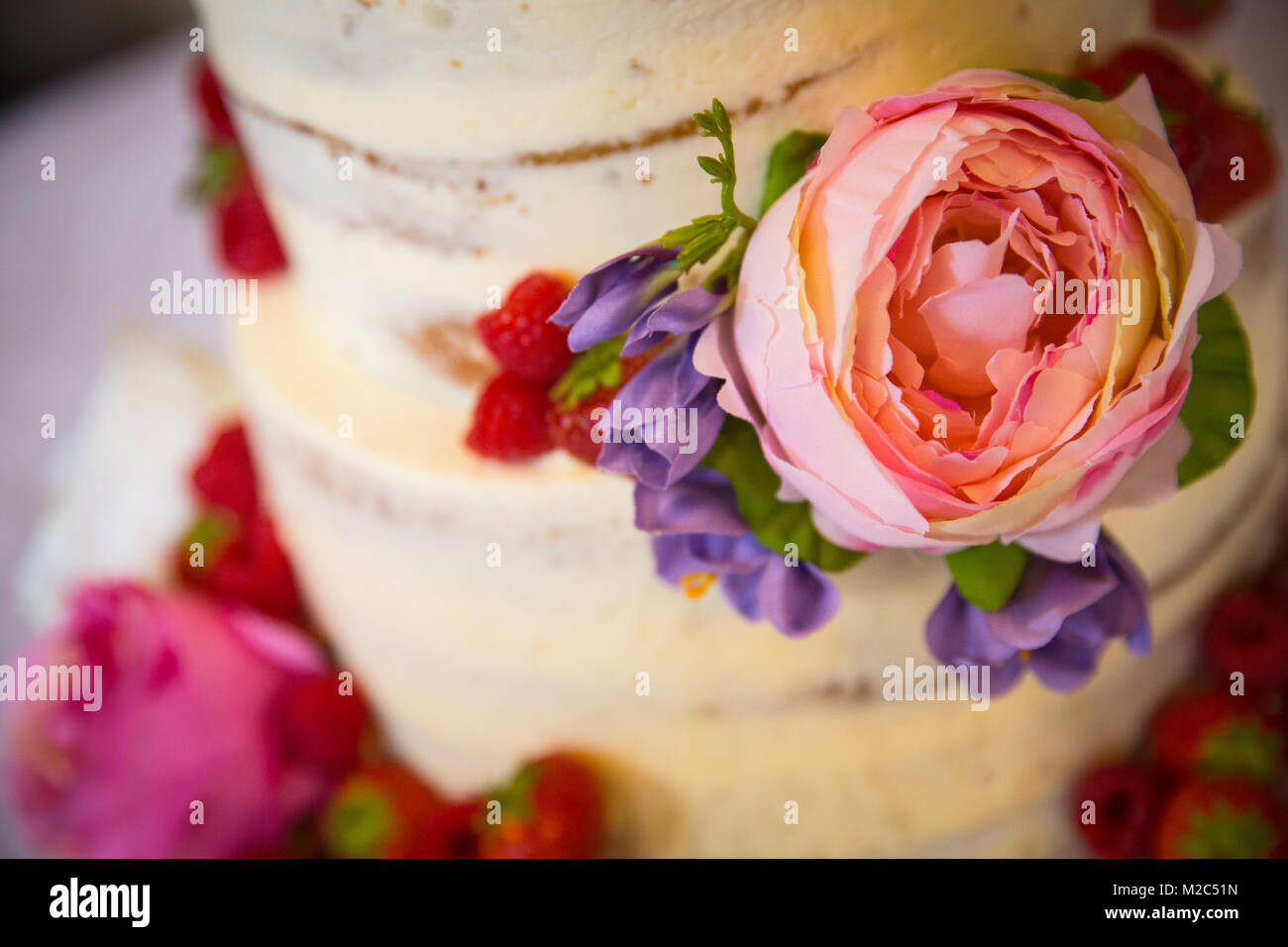 Des fleurs fraîches et des fruits sur les niveaux gâteau de célébration, close-up Banque D'Images