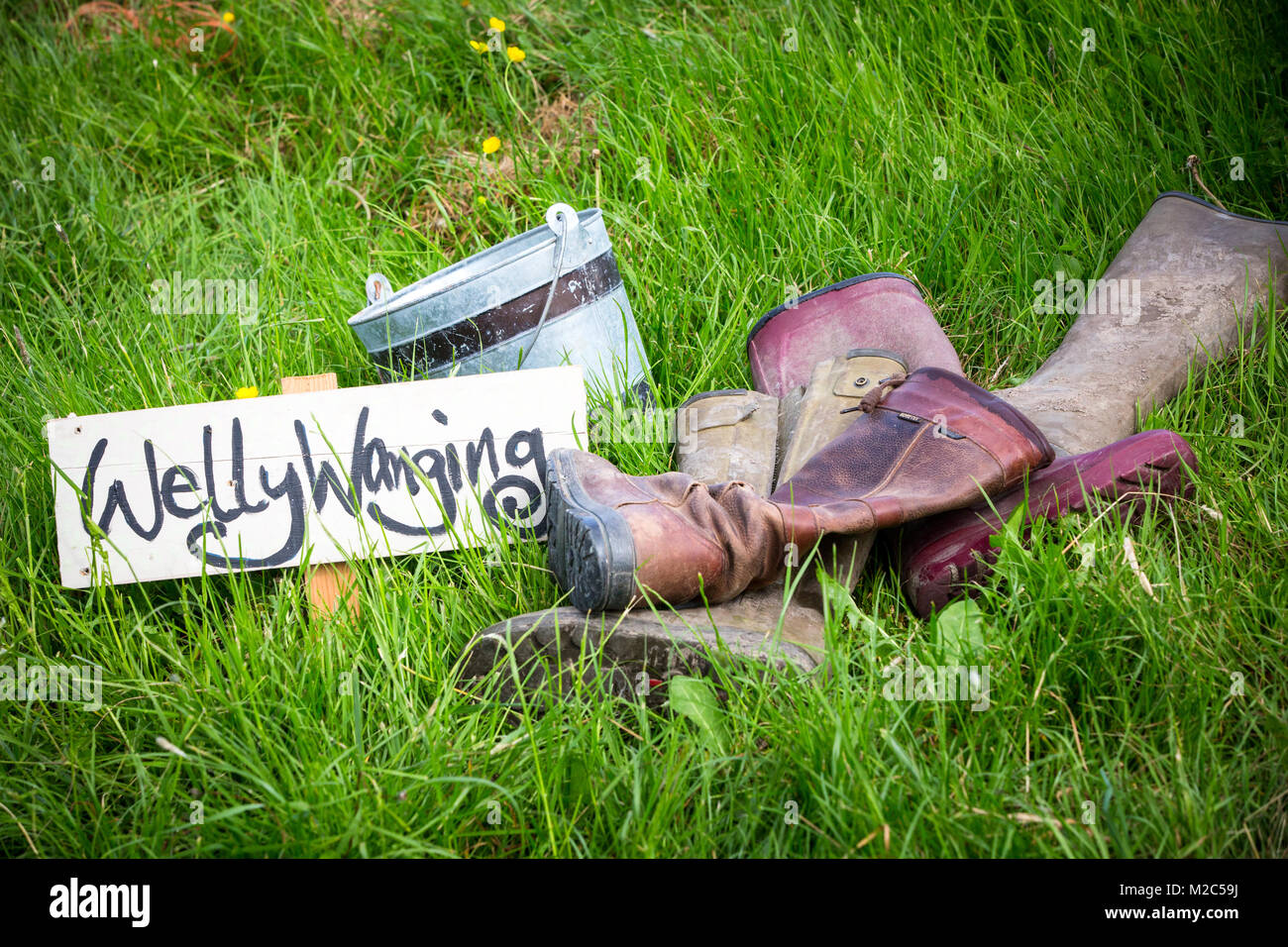 Pile de bottes sur le terrain en herbe, avec 'manuscrites Welly Wanging' sign Banque D'Images