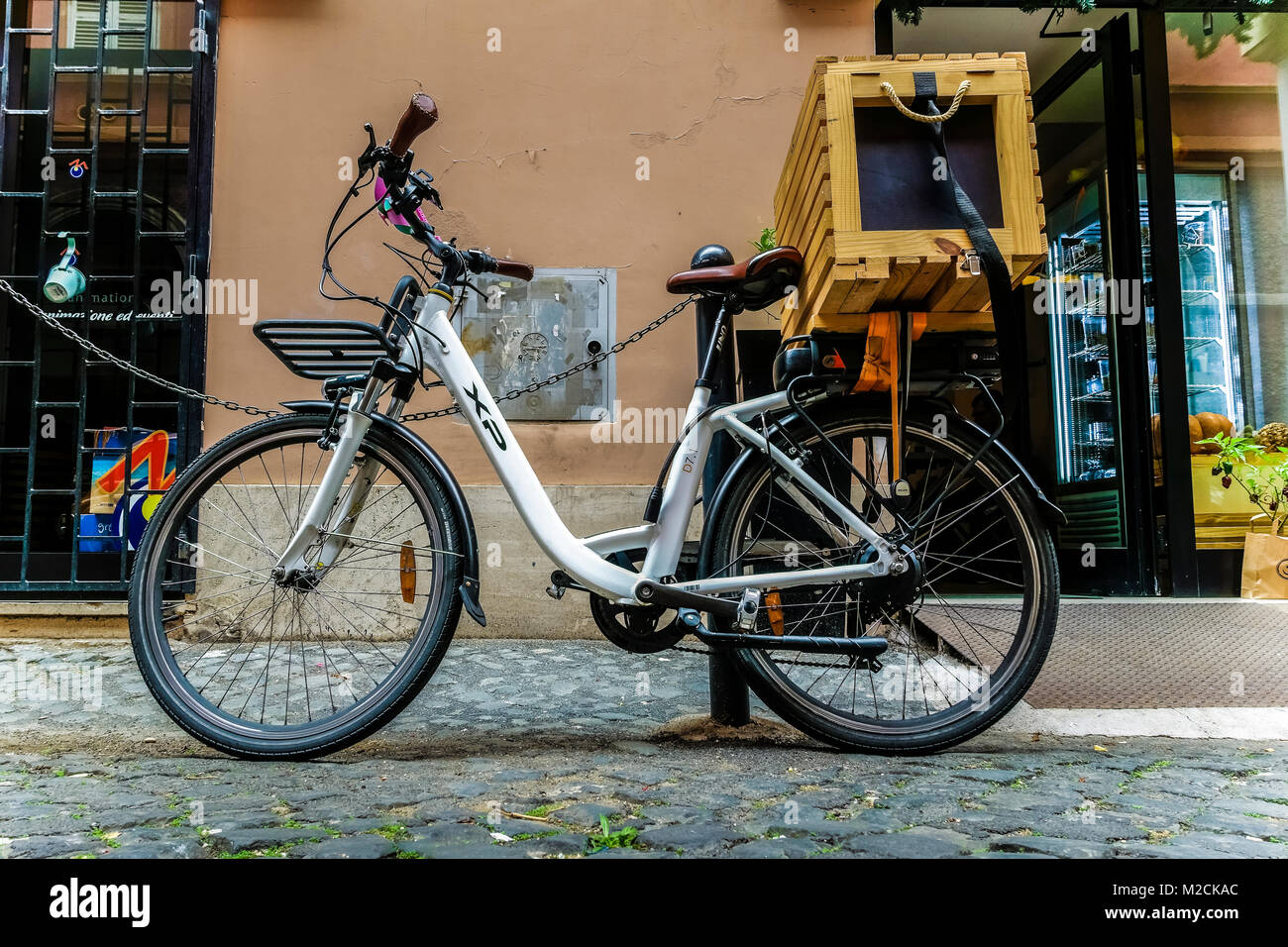 Vélo blanc avec panier de livraison en bois, pour le service de livraison de nourriture, garé et verrouillé devant un magasin. Rome, Italie, Europe, Union européenne, UE Banque D'Images