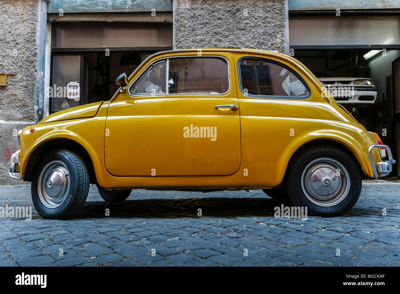 Fiat 500 fabriqué en 1970. Voiture rétro, classique, vintage, de style ancien. Couleur jaune. Garée à l'extérieur d'un atelier de réparation automobile à Rome, Italie, UE. Vue latérale. Banque D'Images