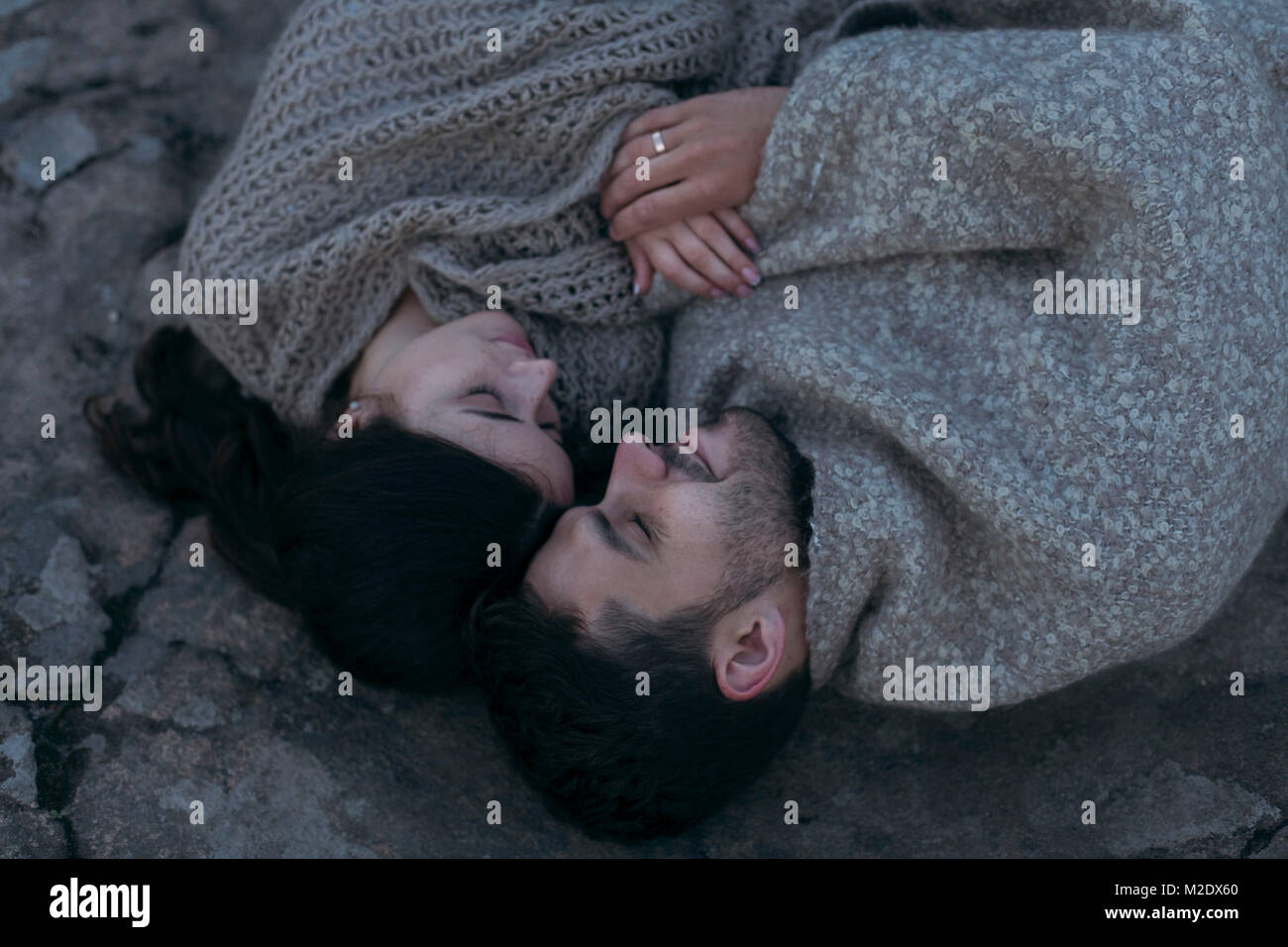 Caucasian couple laying on rock enveloppé dans le contrat cadre Banque D'Images