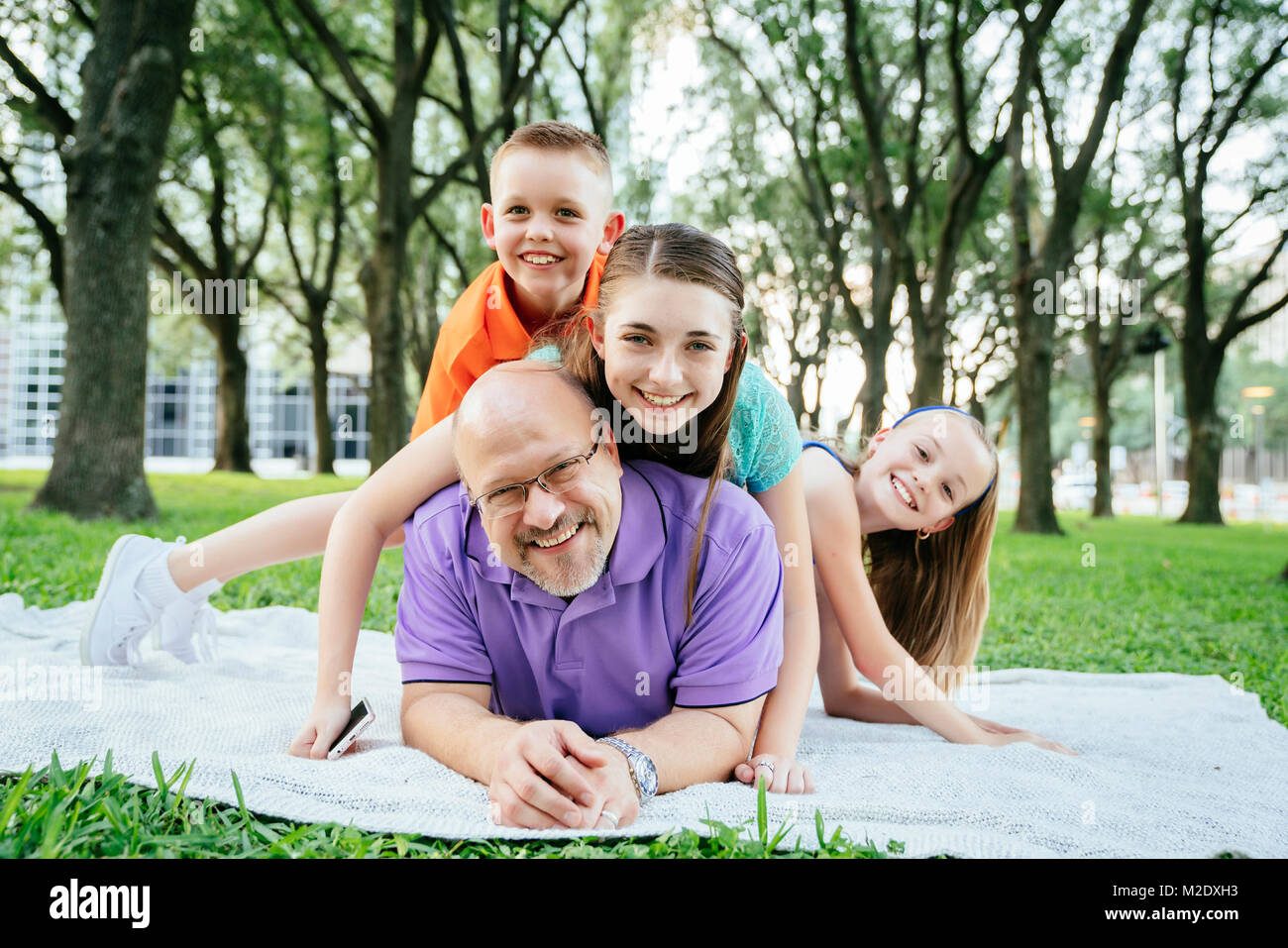 Portrait of Caucasian boy et filles portant sur le dos de père en park Banque D'Images