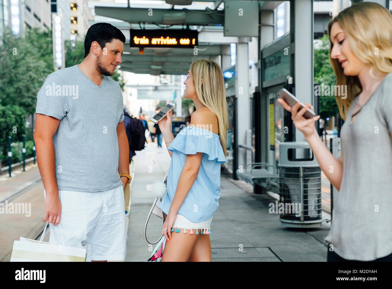 Young woman showing téléphone cellulaire à l'homme à la gare Banque D'Images