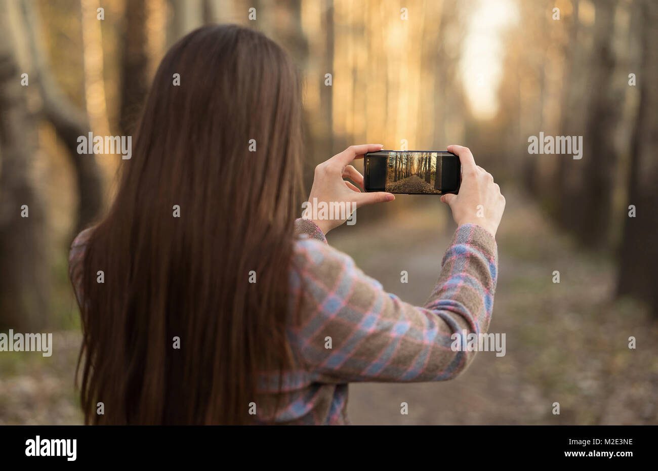 Caucasian woman photographing path with cell phone Banque D'Images