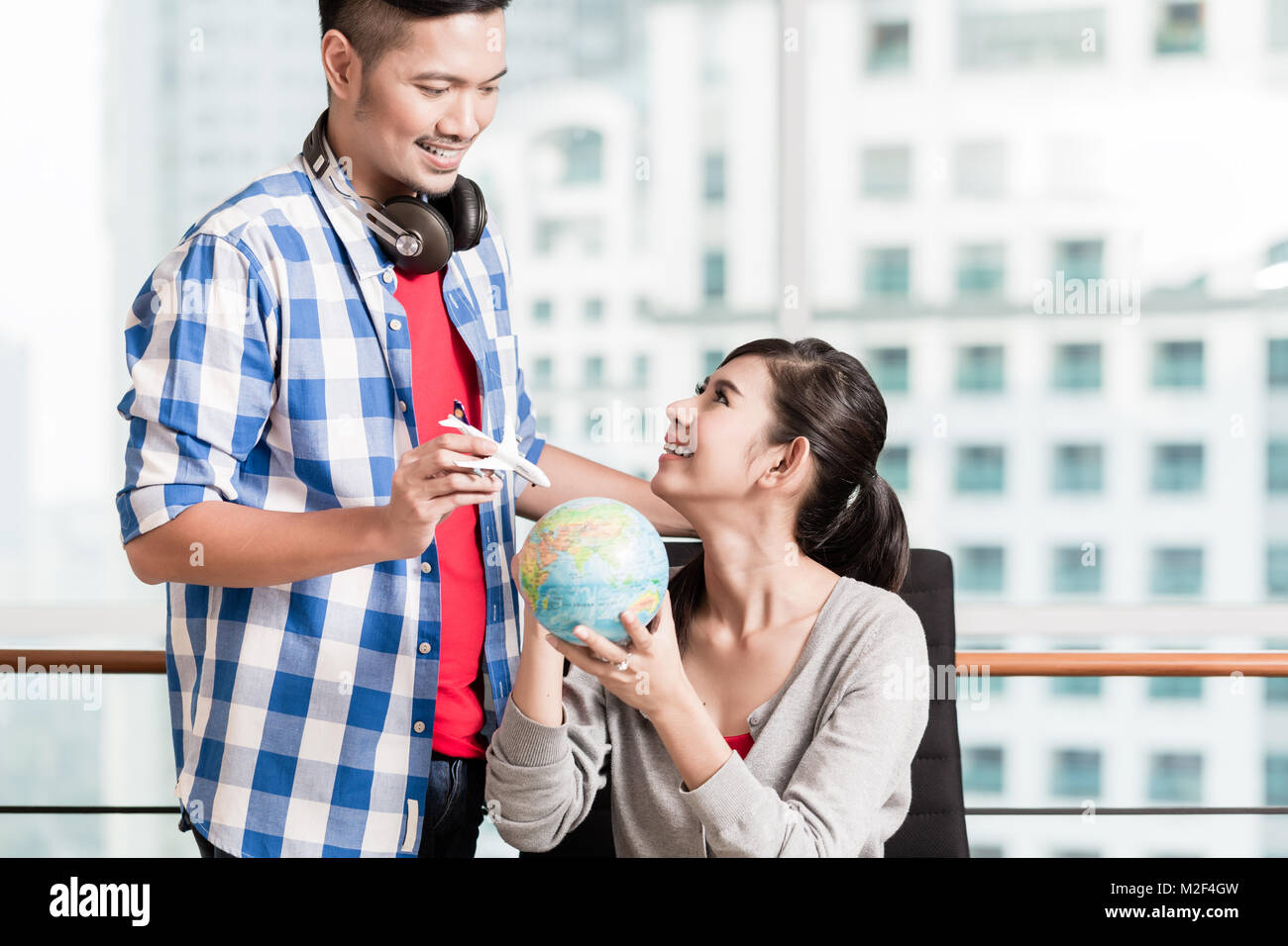Asian couple avec globe et maquette avion en milieu urbain vacances Banque D'Images