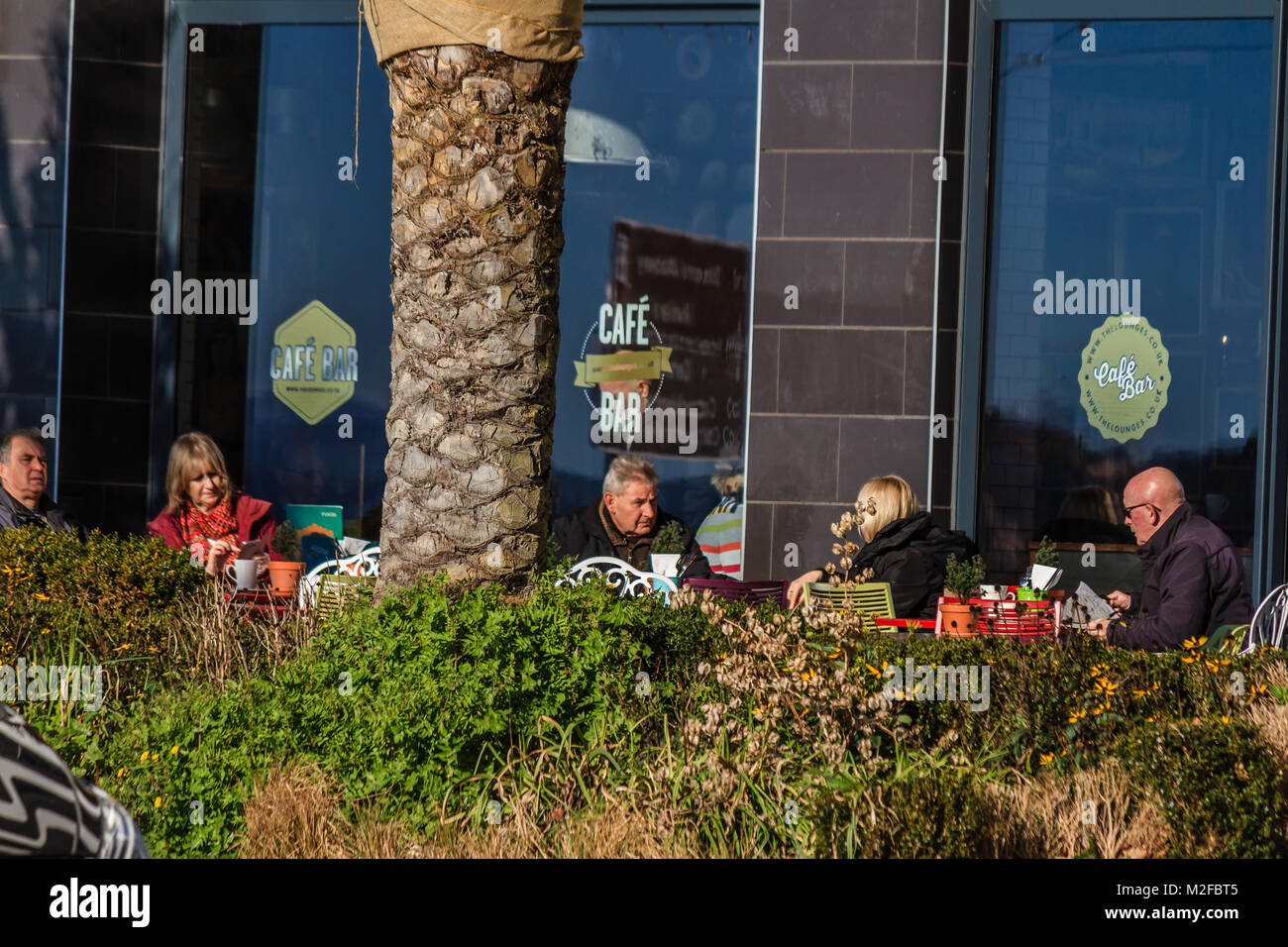 Les gens assis dehors Visto Lounge Cafe au soleil en février 2018. Matin ensoleillé à Torbay Torquay, Devon, UK,. Banque D'Images