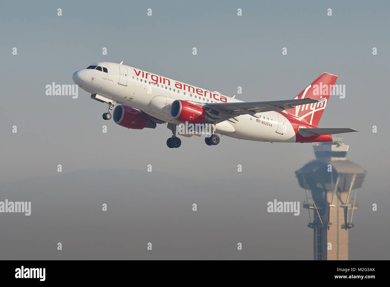 Virgin America Airbus A319 qui décolle de la piste 25 gauche à l'Aéroport International de Los Angeles, la tour de contrôle en arrière-plan. Banque D'Images