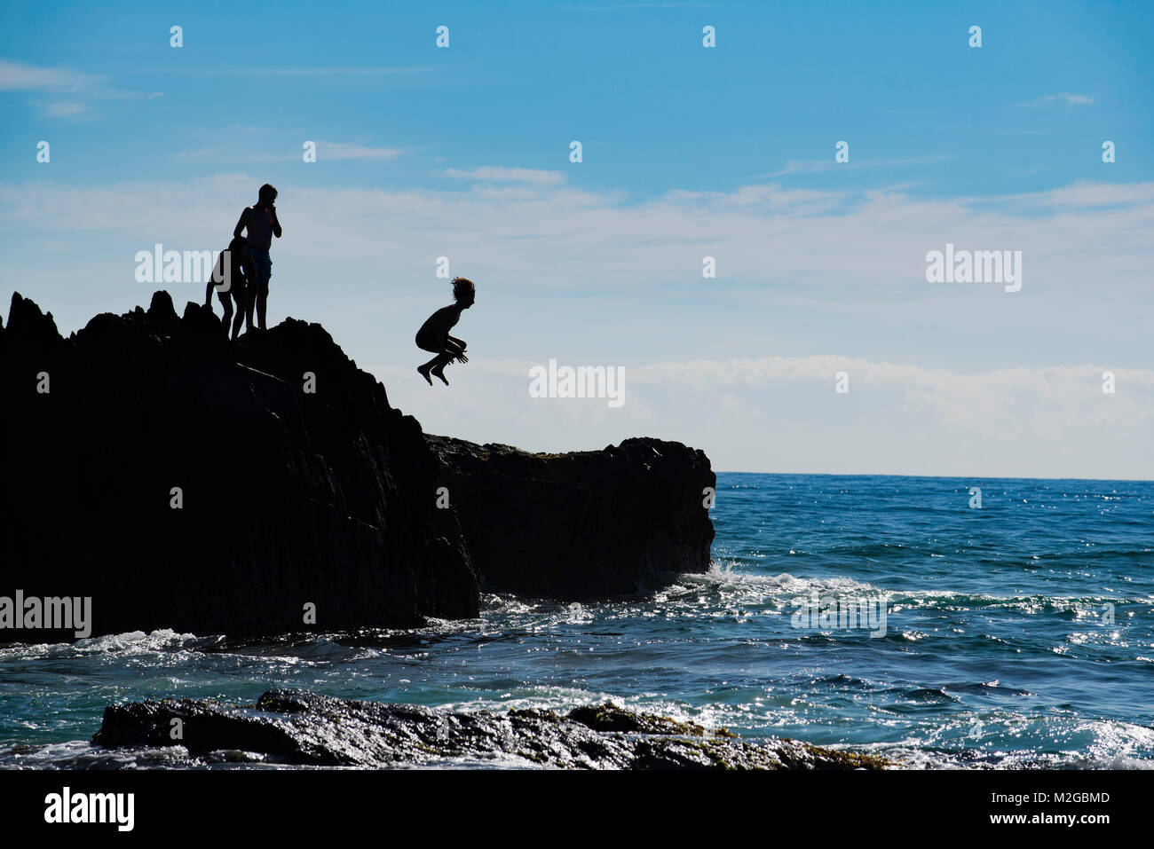 Une silhouette d'une image d'un garçon sautant d'un rocher dans l'océan sur une plage Australienne de la côte est Banque D'Images